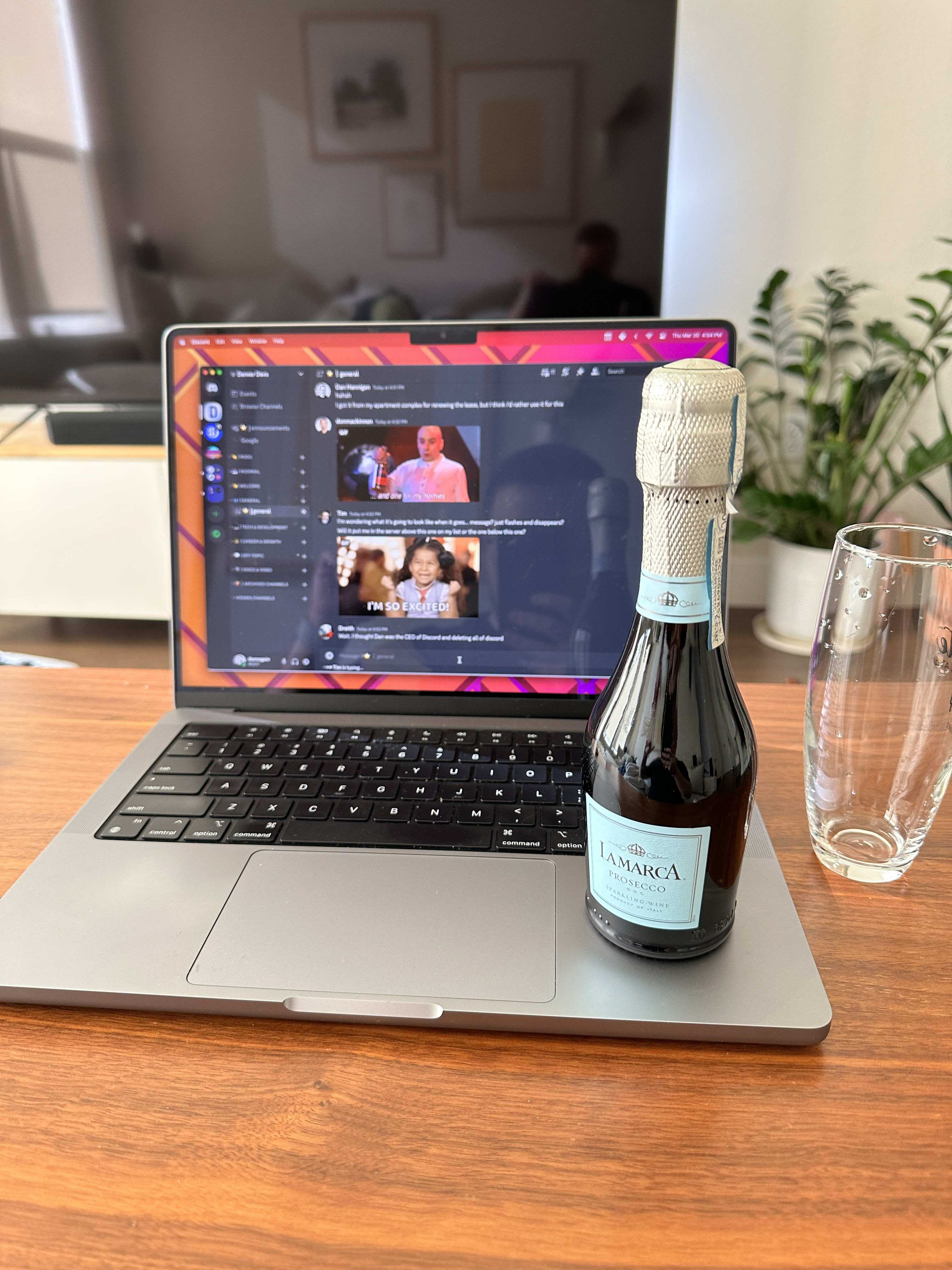 Photo of a laptop with a small bottle of prosecco and a glass