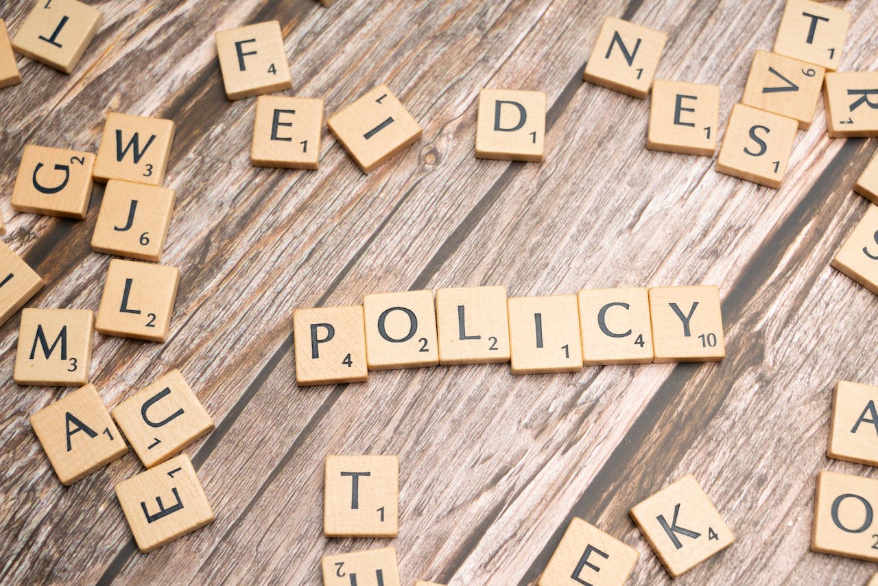 Scrabble tiles form the word policy on a wooden flat surface
