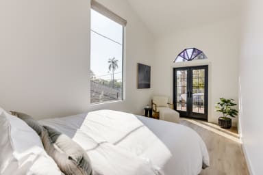 Primary bedroom and French doors opening to a private balcony with seating.