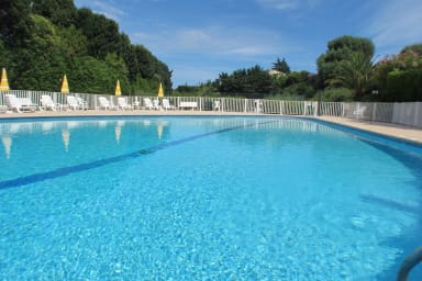 Piscine de la résidence avec chaises, transats et parasols.