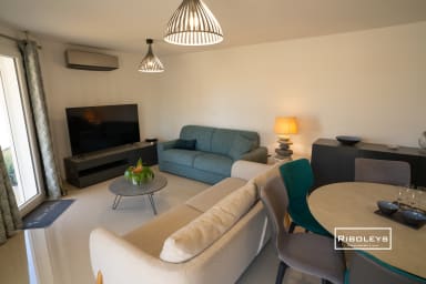 Grande pièce de vie climatisée avec table à manger et cuisine ouverte.