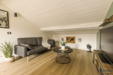 Espace séjour avec télévision et plafond en pente
