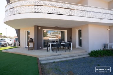 Grande terrasse avec coin repas et barbecue électrique.