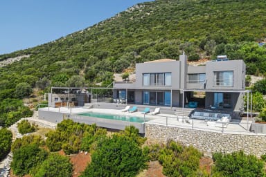 Striking modern architecture meets infinity pool, framed by vibrant greenery.