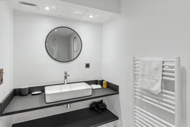 Espace lavabo élégant et moderne, équipé d’un miroir rond raffiné.