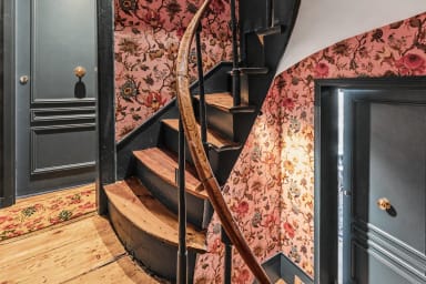 Escalier intérieur en bois et papier peint fleuri pour une entrée chaleureuse.