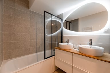 Salle de bain moderne avec doubles vasques et plateau en bambou ainsi que...