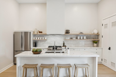 Modern kitchen with a white island, bar seating, and open shelving