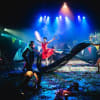 The company perform "Pyramus and Thisbe" with Zoe Campbell as Snug/Lion (in orange mask), Eli Caldwell as Flute / Thisbe (red dress) and David Clayton as Bottom / Pyramus (far right)
