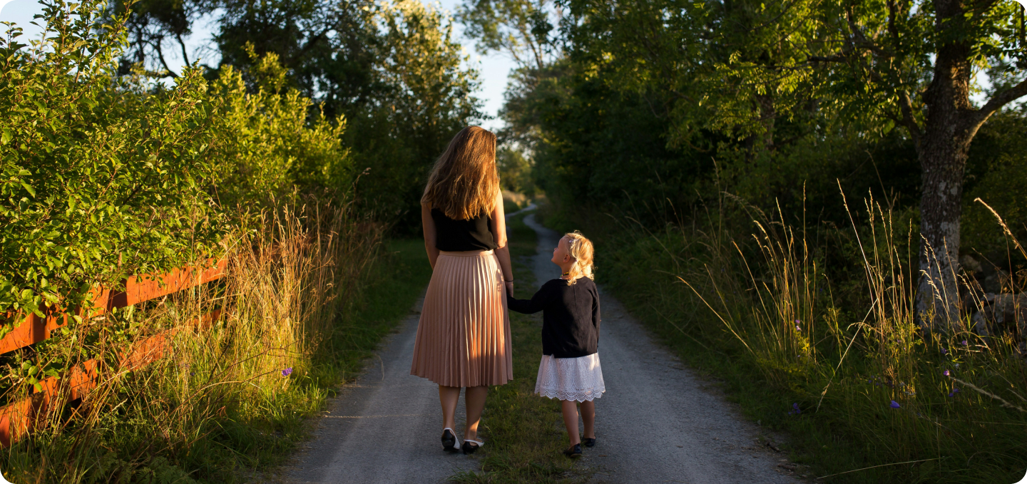 Frau mit Mädchen an der Hand auf einem Weg