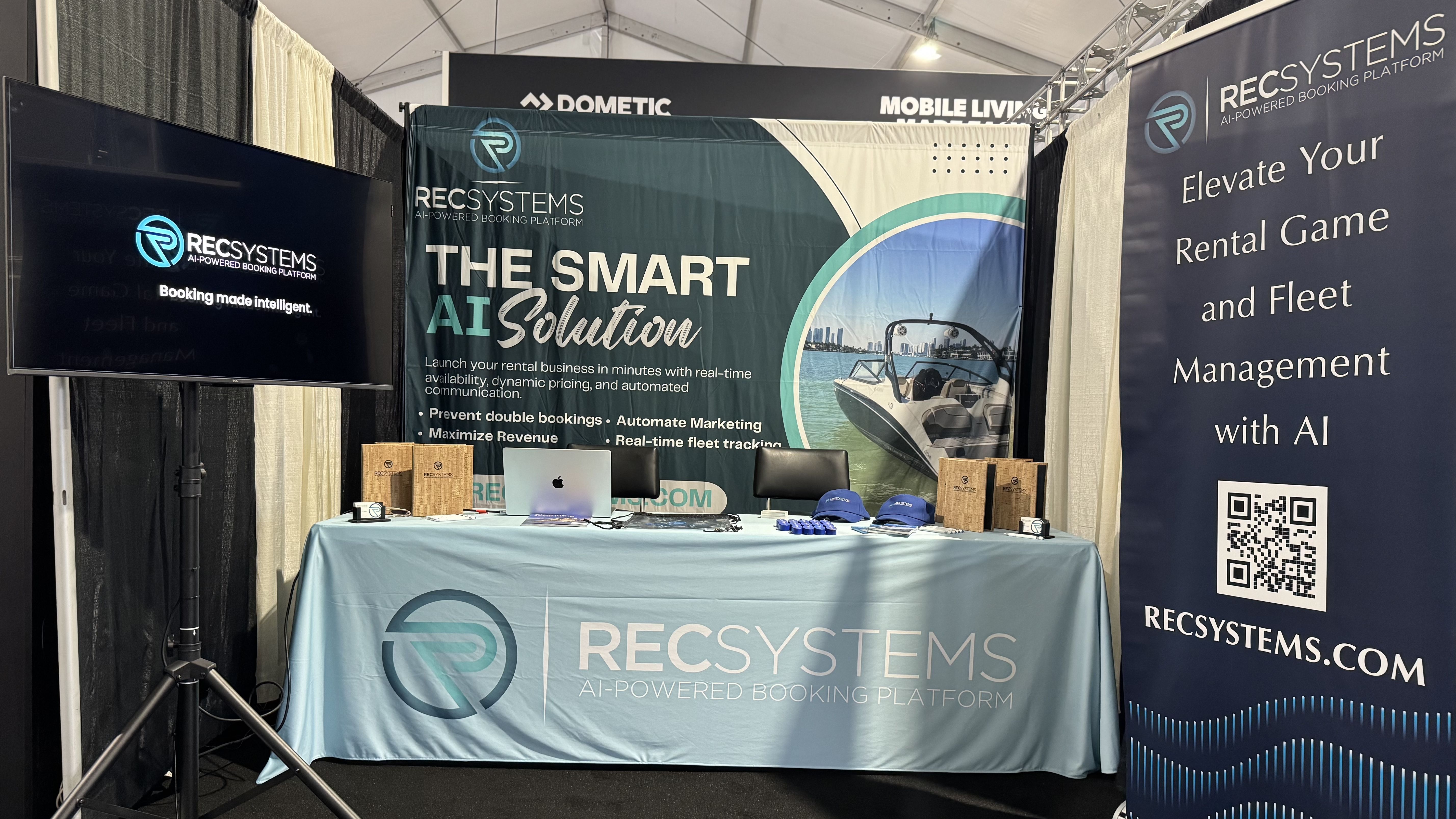 RecSystems.com exhibition booth featuring branded displays, banners highlighting smart AI rental solutions, and informational materials on an event table