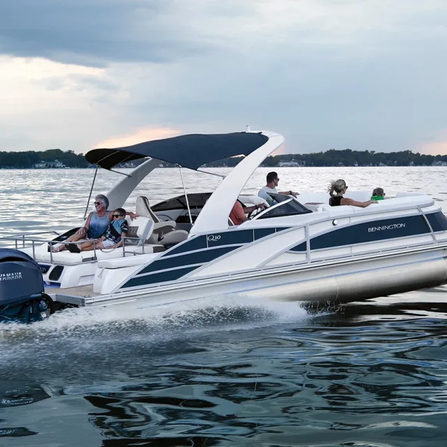 A group of people enjoying a ride on a sleek powerboat in a calm lake under a cloudy sky