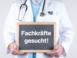 Arzt mit einem Schild Fachkräfte gesucht