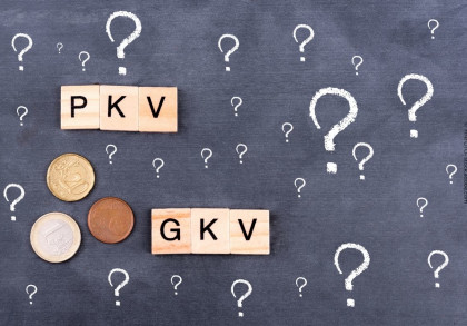 Ein Bild zeigt eine Tafel mit vielen Fragezeichen darauf. In der Mitte befinden sich zwei Gruppen von Holzklötzchen mit den Buchstaben "PKV" und "GKV".
