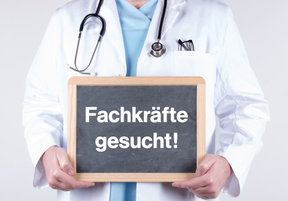 Arzt mit einem Schild Fachkräfte gesucht