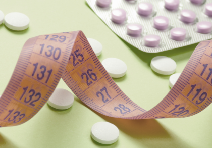 Orangefarbenes Maßband zwischen weißen und violetten Tabletten auf hellgrünem Hintergrund als Symbol für GLP-1-Abnehmtabletten und Gewichtsreduktion.