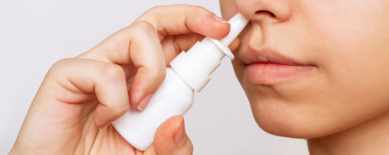 Eine Frau spritzt sich das Nasenspray in die Nase.