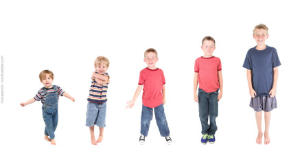 Fünf Jungen unterschiedlicher Altersstufen stehen in einer Reihe vor einem weißen Hintergrund. Von links nach rechts sind die Jungen in aufsteigender Größe und Altersstemmen aufgereiht.