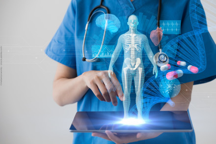 Eine Person in blauer medizinischer Kleidung mit Stethoskop zeigt auf ein Tablet. Über dem Tablet schwebt ein Hologramm eines menschlichen Skeletts, umgeben von weiteren medizinischen Symbolen wie Gehirn, Herz, DNA-Strang und Tabletten.