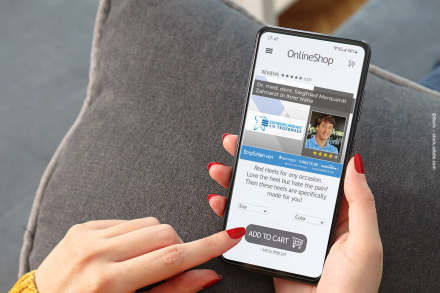 Eine Hand hält ein Smartphone, das eine Online-Shop-Seite anzeigt. Die Seite wirbt für rote Schuhe. Über der Werbung befindet sich ein Werbebanner für einen Zahnarzt namens Dr. med. dent. Siegfried Marquardt, der in der Nähe ist.