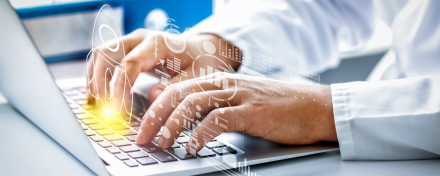 Hände eines Arztes oder Health-Professionals tippen auf Laptop, um Daten für digitales Gesundheitsmarketing oder Medical SEO zu analysieren, mit eingeblendeten Grafiken.