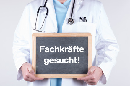 Arzt mit einem Schild Fachkräfte gesucht