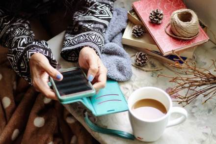 Frau tippt in ein Handy um ein Privatrezept einzulösen an einem Kaffeetisch