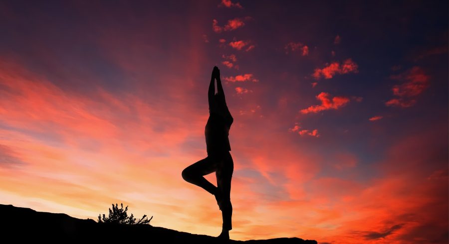 Mit Thai Yoga die innere Mitte finden: Eine Frau macht Yoga Übungen bei Sonnenuntergang