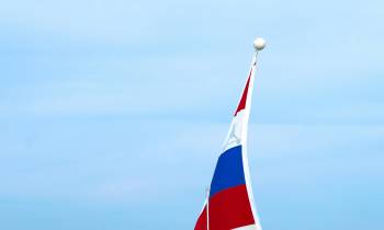a flag on the back of a boat next to a body of water