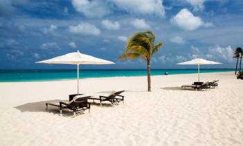 a couple of lawn chairs sitting on top of a sandy beach