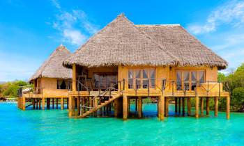 a large pool of water in front of a house with Bora Bora in the background