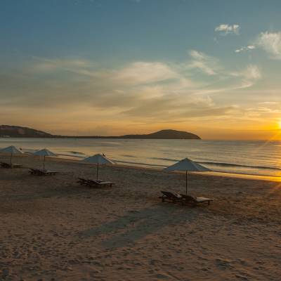 a sunset over a beach next to a body of water