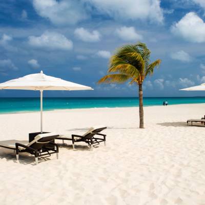 a couple of lawn chairs sitting on top of a sandy beach