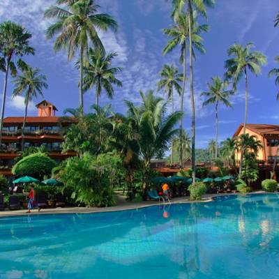 a pool next to a body of water surrounded by palm trees
