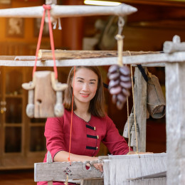 Women in thai dress are weaving with ancient weaving machines