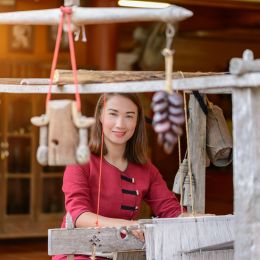 Women in thai dress are weaving with ancient weaving machines