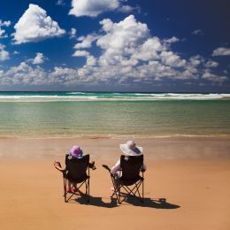 Zwei Camper sitzen in Campingstühlen am Strand