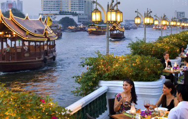 Elegant gekleidete Menschen dinieren am Flussufer in Bangkok