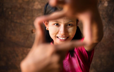 Schöne junge Frau aus Myanmar lächelt spielerisch in die Kamera