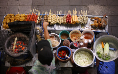 Verkäufer eines Straßenstandes bereitet thailändische Spezialitäten zu
