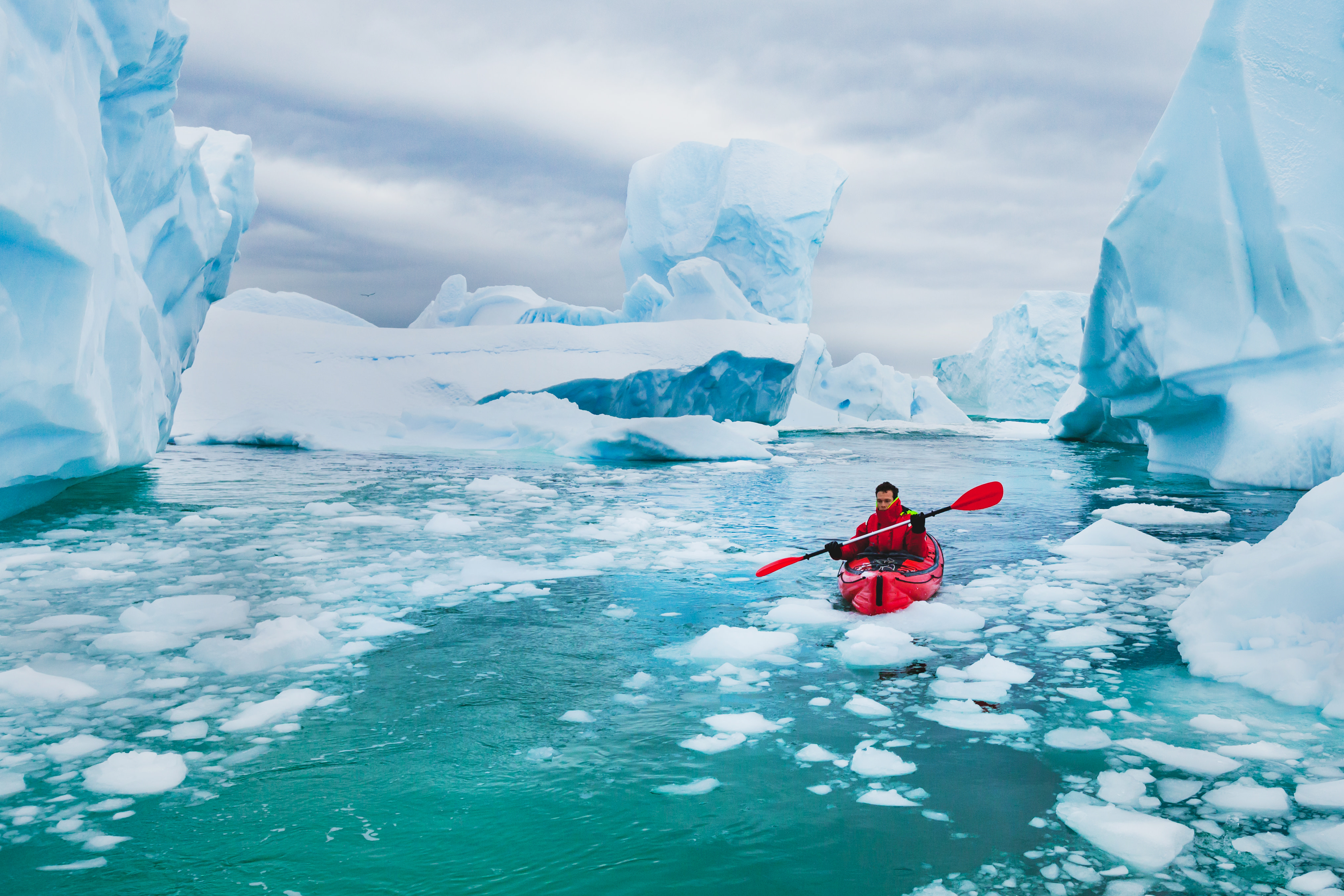 extreme tourism, winter kayaking in Antarctica, adventurous man paddling on sea kayak between icebergs Man paddling on kayak between ice in Antractica, near Pleneau Island