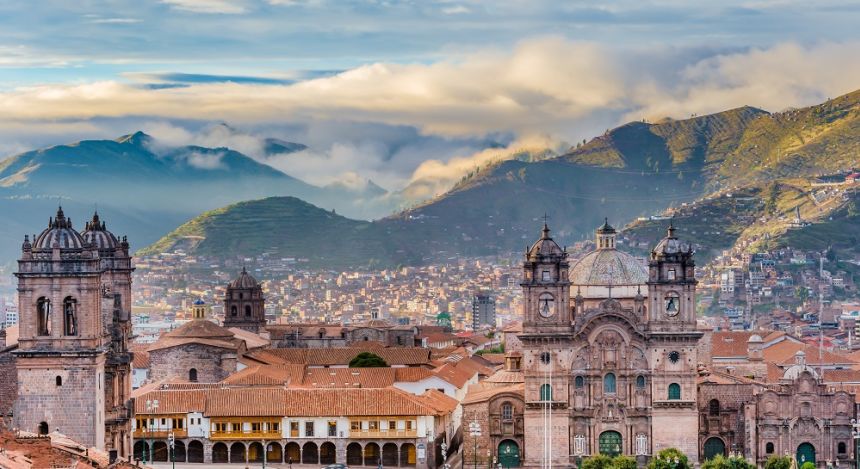 Stadtpanorama von Cusco mit der Kathedrale im Vordergrund und dem bewölkten Anden-Gebirge im Hintergrund, Peru