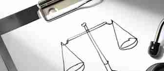 A sheet of paper with a hand-drawn scales of justice rests on a clipboard. A stethoscope is partially visible beside it, suggesting a connection between law and healthcare.