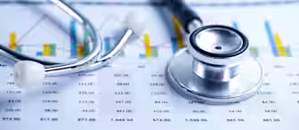 A stethoscope rests on a financial document with charts and tables. The image emphasizes the intersection of healthcare and finance, illustrating numerical data and bar graphs alongside the medical tool.