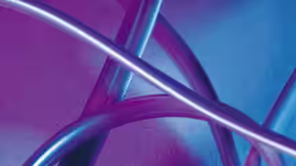 A close-up image of several metallic tubes intertwined against a gradient background of pink and blue hues. The tubes reflect the colors, creating a visually abstract and vibrant composition.