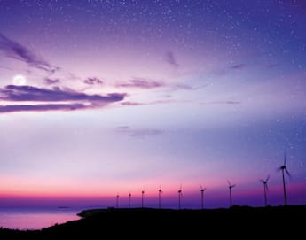 A serene scene of a coastal landscape at dusk, featuring a row of wind turbines silhouetted against a vibrant sky with shades of purple, pink, and blue. The moon is partially visible amidst wispy clouds, and the sea reflects the twilight hues. Stars dot the sky.