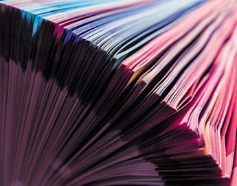 Close-up of a book with colorful pages fanned out. The edges of the pages display a spectrum of vibrant colors ranging from pink to blue, creating a striking and visually appealing pattern.