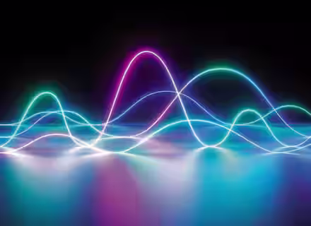 A digital abstract image featuring colorful waveforms of neon light against a black background. The waves, in shades of blue, purple, and pink, appear to overlap and flow, creating a vibrant, dynamic visual effect on a reflective surface.