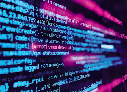 A close-up of computer code displayed on a screen, with lines of code in vibrant blue, pink, and purple colors. One line of text is highlighted in red, stating "[error] virus detected," indicating a security issue within the code.