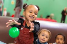 little girl reaching for a ball in a ball pit